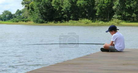 Téléchargez les photos : Petit garçon pêchant seul au lac - en image libre de droit