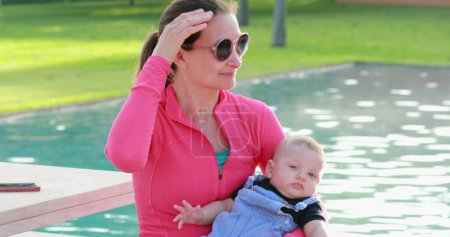 Téléchargez les photos : Femme tenant un nouveau-né près de l'eau de la piscine - en image libre de droit