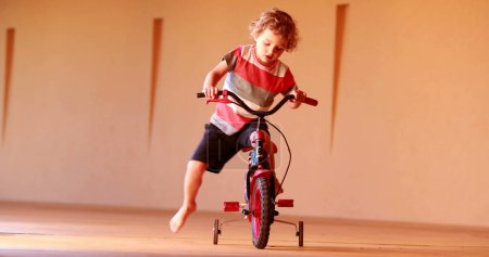 Téléchargez les photos : Small boy learning to ride tricycle - en image libre de droit