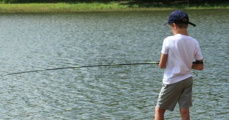 Téléchargez les photos : Jeune garçon pêche au lac - en image libre de droit