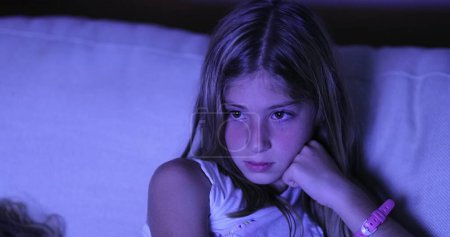 Photo for Candid child girl watching TV screen in the dark, Little girl looking at movie - Royalty Free Image