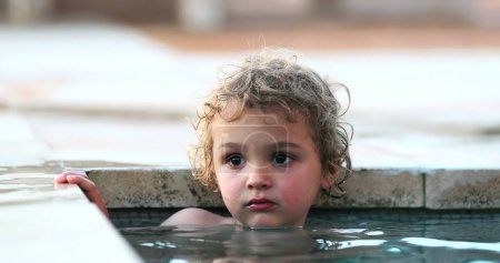 Thoughtful Portrait of child inside swimming pool relaxing thinking