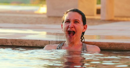 Photo for Tired woman yawning inside swimming pool water and then smiling casual and candid - Royalty Free Image