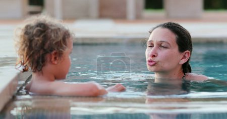 Téléchargez les photos : Interaction mère-enfant à l'eau de la piscine - en image libre de droit