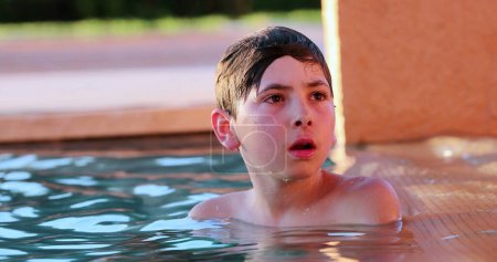 Foto de Pensativo niño en la piscina pensando en relajarse dentro del agua - Imagen libre de derechos