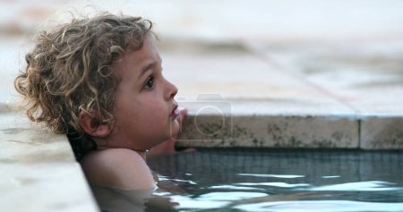 Foto de Pensive Toddler boy child inside swimming pool water thinking - Imagen libre de derechos