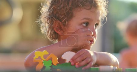 Photo for Toddler boy playing with puzzle pieces thinking and learning - Royalty Free Image