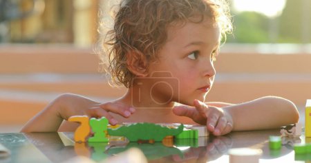 Photo for Toddler child boy playing with toys outside in the sunlight, small boy concentrating - Royalty Free Image