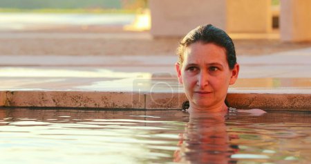 Foto de Pensativa mujer pensativa pensando en el agua de la piscina - Imagen libre de derechos