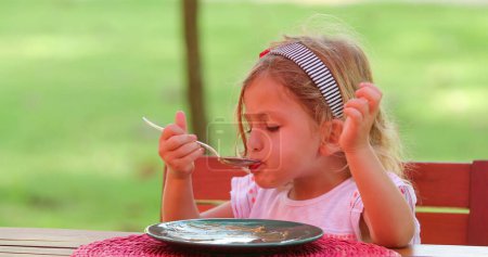 Photo for Candid pretty little girl eating sweet dessert with spoon - Royalty Free Image