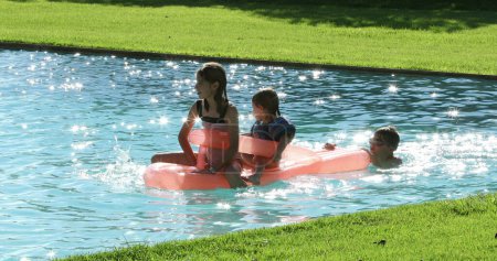 Foto de Niños jugando el agua de la piscina en la parte superior del colchón inflable - Imagen libre de derechos