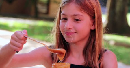 Téléchargez les photos : Petite fille mangeant un dessert. Petite collation enfant scooping avec cuillère - en image libre de droit