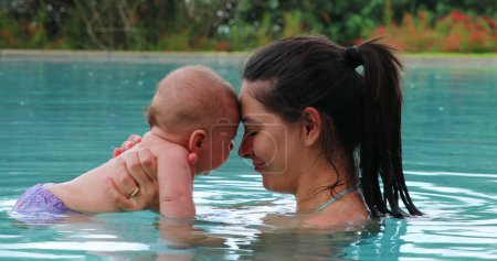 Foto de Mother and baby interaction at the swimming pool eskimo kiss - Imagen libre de derechos