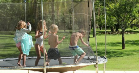 Téléchargez les photos : Enfants sautant à l'intérieur trampoline à l'extérieur - en image libre de droit