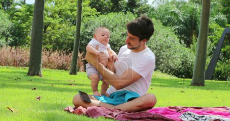 Photo for Young Father holding baby toddler outside in nature at the park - Royalty Free Image