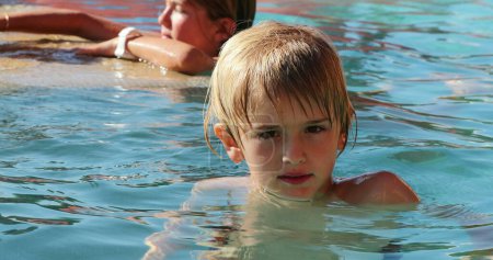 Foto de Retrato de niño rubio dentro del agua en la piscina mirando a la cámara - Imagen libre de derechos