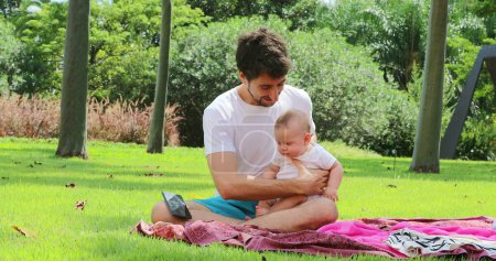 Téléchargez les photos : Jeune père tenant bébé tout-petit dehors dans la nature au parc - en image libre de droit