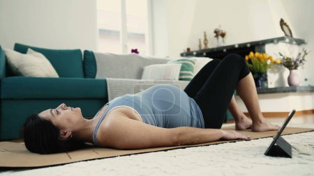 Werdende Mutter, die zu Hause Yoga-Übungen zur Linderung von Rückenschmerzen macht, priorisiert Körperwellness während der späten Schwangerschaft im dritten Trimester