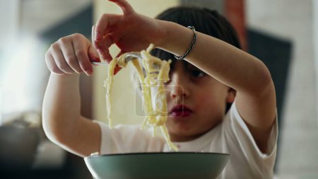 Photo for Spaghetti Delight - Little Boy Learning to Spin Fork While Eating Pasta, Enjoying Mealtime Utensil Use - Royalty Free Image