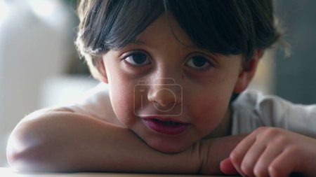 Porträt eines 5-jährigen kaukasischen Jungen, der auf einen Tisch gestützt in die Kamera blickt. Nahaufnahme des hübschen Kindes