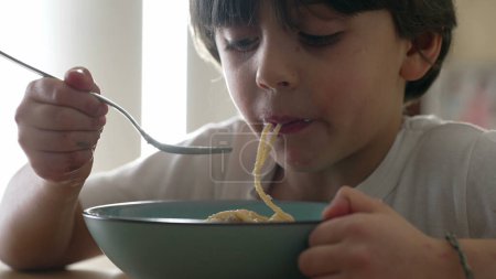 Photo for Cheese Spaghetti Delight - Hungry 5-Year-Old Enjoying Pasta, Close-Up of Boy Eating - Royalty Free Image