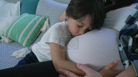 5-Year-Old Boy Lovingly Embracing Mother's Pregnant Belly on Couch, Heartfelt Family Moment seated on couch during relaxing afternoon. maternal concept