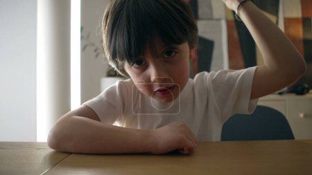 Photo for Assertive child hits table surface with hand. 5 year old boy demanding attention while looking at camera, close-up face and fist - Royalty Free Image