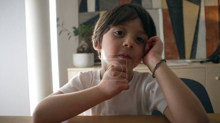 Téléchargez les photos : Petit garçon pensif réfléchissant à une solution à un problème, gros plan sur le visage d'un beau caucasien de 5 ans kif avec la main dans le menton avec une expression réfléchie - en image libre de droit