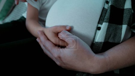 Foto de Las manos del niño y la madre abrazando el embarazo del vientre del tercer trimestre de manera tierna - Imagen libre de derechos
