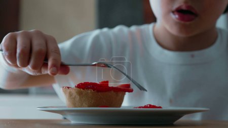 Photo for Child Struggling to Reach Cheesecake with Fork - Close-Up View of Sugary Treat Topped with Strawberries on Plate - Royalty Free Image