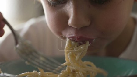 Photo for Child spinning spaghetti with fork close-up hand and face. Little boy learning to eat pasta, carb-rich food - Royalty Free Image