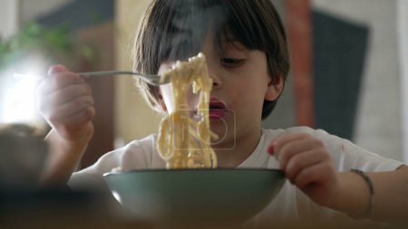 Délice des spaghettis - Petit garçon essayant de faire tourner la fourchette en mangeant de la nourriture pour pâtes pendant les repas. Enfant appréciant apprendre à utiliser des ustensiles