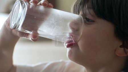 Téléchargez les photos : Enfant assoiffé boire un verre d'eau - étancher la soif. 5 ans profil de garçon gros plan visage - en image libre de droit