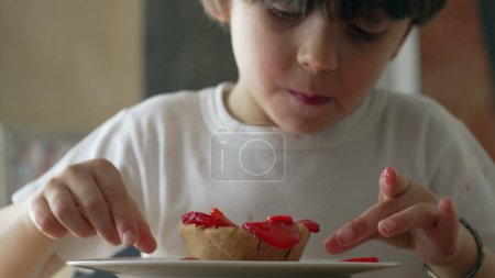 Photo for One small boy savoring cheesecake dessert. 5 year old child grabbing sugary food from plate - Royalty Free Image