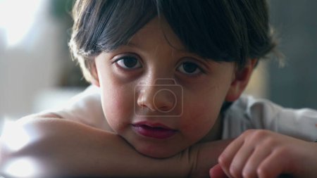 Retrato de un niño caucásico de 5 años mirando a la cámara, apoyado en la mesa. primer plano de la cara de niño guapo