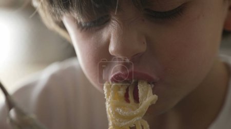 Foto de Espaguetis giratorios infantiles con tenedor mano y cara. Niño aprendiendo a comer pasta, comida rica en carbohidratos - Imagen libre de derechos