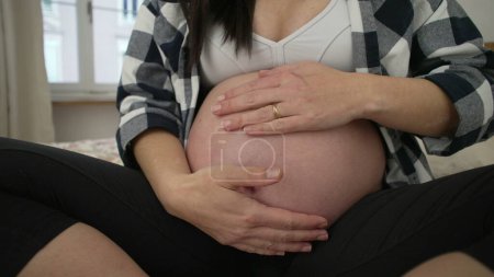 Téléchargez les photos : Femme enceinte caresse bébé à naître, gros plan hant toucher doucement ventre troisième trimestre - en image libre de droit