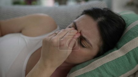 Téléchargez les photos : Stressé 30s femme gros plan visage posé sur le canapé fronçant les sourcils mettre les mains dans le front lutte avec les défis de la vie et des maux de tête - en image libre de droit