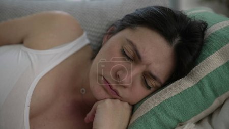 Téléchargez les photos : Stressé 30s femme gros plan visage posé sur le canapé fronçant les sourcils mettre les mains dans le front lutte avec les défis de la vie et des maux de tête - en image libre de droit