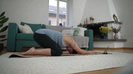 Prenatal exercise of 30s pregnant woman stretching body in living room at home, taking care of wellbeing and back health during late stage pregnancy