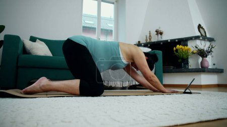 Femme enceinte faisant de l'exercice à la maison dans le salon, prenant soin des maux de dos pendant la grossesse du troisième trimestre