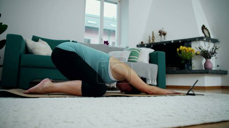 Schwangere turnt zu Hause im Wohnzimmerboden und pflegt Rückenschmerzen während der Schwangerschaft im dritten Trimester