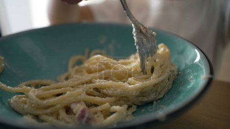 Gros plan du petit garçon filant des pâtes spaghetti à la fourchette. Enfant de 5 ans mangeant de la nourriture riche en glucides pendant les repas, enfant apprenant à manger un plat italien