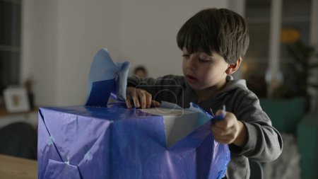 Photo for Child unwrapping present gift, one small boy tearing paper from package eagerly wanting to open box - Royalty Free Image