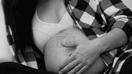 Caricia del vientre tierna de la mujer monocromática de los años 30, embarazo tardío, primer plano del tacto del tercer trimestre en blanco y negro