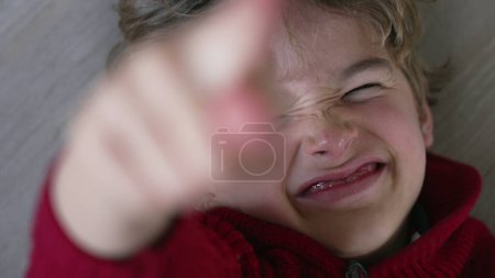 Photo for One happy young boy grinning and grimacing towards camera, laid on floor looking up. Close-up face grinning capturing happiness and youthfulness - Royalty Free Image