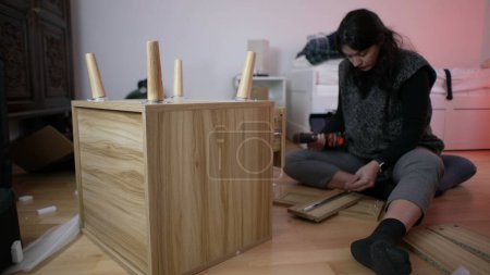 Mujer montando muebles en casa con máquina de perforación, persona moviéndose a nuevo concepto de hogar - armando mesa de noche