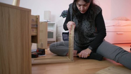 Foto de Entusiasta de la mejora del hogar Mujer Elaboración de mesita de noche, mostrando habilidades de bricolaje en el montaje de muebles para la configuración del hogar - mudanza a un nuevo concepto de casa - Imagen libre de derechos