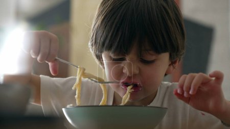 Freude am Essen - Nahaufnahme eines kleinen Jungen, der Spaghetti genießt und kohlenhydratreiche Pasta genießt