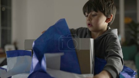 Kind packt Geschenk eifrig aus, kleiner Junge reißt Papier aus Paket, um zu entdecken, was drin ist